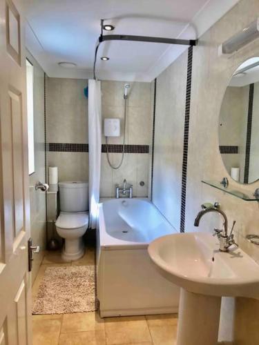 a bathroom with a tub and a toilet and a sink at Isle of Wight Seaview in Shanklin