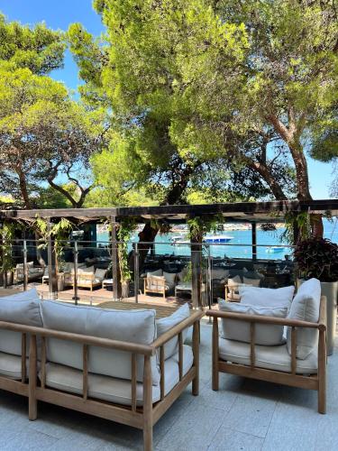 two chairs and a table on a patio with trees at Hotel Cavtat in Cavtat