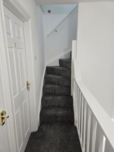 a hallway with a staircase with white walls and a door at Realwood Homes- Broomhill Road in Nottingham