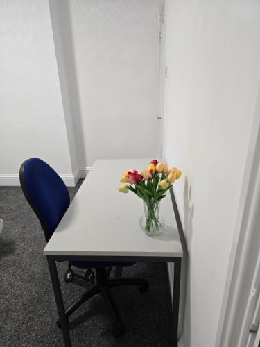 a vase of flowers on a table with a chair at Realwood Homes- Broomhill Road in Nottingham