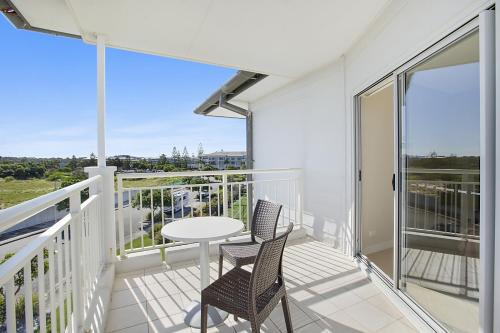 a balcony with two chairs and a table at The Pool Resort Kingscliff - Private Apartments by Holiday Management Company in Kingscliff