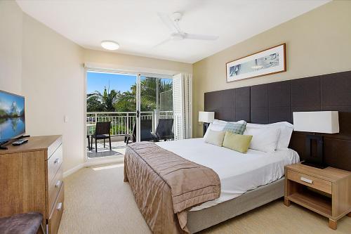a bedroom with a large bed and a balcony at The Pool Resort Kingscliff - Private Apartments by Holiday Management Company in Kingscliff