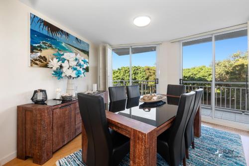 a dining room with a table and chairs and large windows at The Pool Resort Kingscliff - Private Apartments by Holiday Management Company in Kingscliff