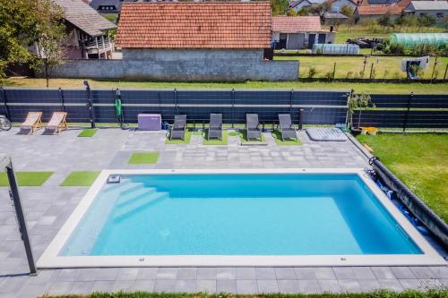 an empty swimming pool with chairs in a yard at Villa Joy With Pool and Hot Tub - Happy Rentals in Sračinec
