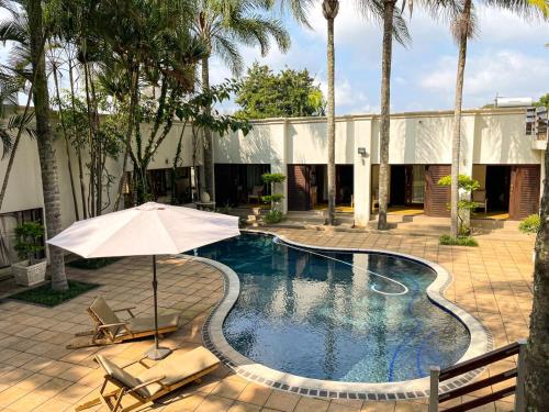 a swimming pool with two chairs and an umbrella at Telestai Guest House in White River