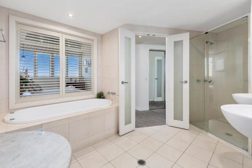 a bathroom with a tub and a sink and a window at The Pool Resort Kingscliff - Private Apartments by Holiday Management Company in Kingscliff