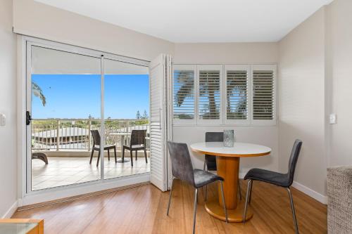 a dining room with a table and chairs and a balcony at The Pool Resort Kingscliff - Private Apartments by Holiday Management Company in Kingscliff
