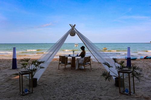 a woman sitting at a table in a tent on the beach at Sichon Cabana Beach Resort in Sichon