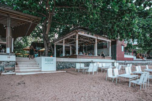 a restaurant with chairs and tables and a building at Sichon Cabana Beach Resort in Sichon