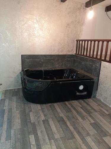 d'une grande baignoire noire installée dans l'angle d'une pièce. dans l'établissement la chaumière des barthes, à Laussonne