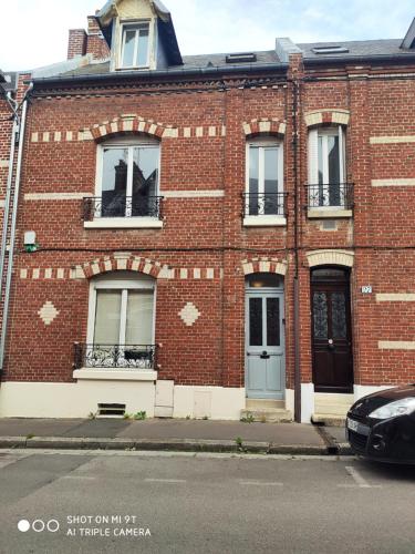 a red brick building with windows on a street at Chaleureux T2 au style VINTAGE - rue gratuite in Amiens