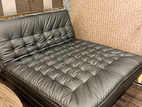 a black leather couch in a room at 1st STEP HOTEL ファーストステップホテル in Tokyo
