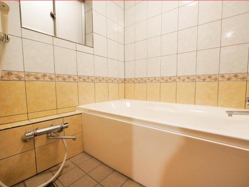 a bathroom with a white tub and a mirror at 1st STEP HOTEL ファーストステップホテル in Tokyo