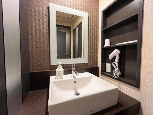 a bathroom with a white sink and a mirror at 1st STEP HOTEL ファーストステップホテル in Tokyo
