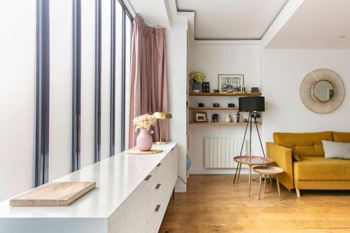 un salon avec une table et un canapé jaune dans l'établissement Appartement rénové une chambre avec espace de travail, à Suresnes