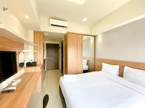 a hotel room with a bed and a television at Minimalist and Homey Studio Apartment at Mustika Golf Residence By Travelio in Cikarang