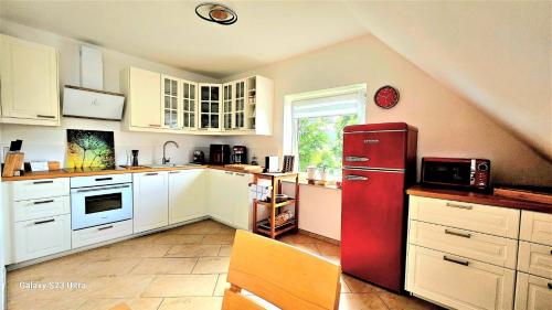 a kitchen with a red refrigerator and white cabinets at Lüneburg-Melbeck, 105 qm mit Fernsicht, ruhige Sackgasse, Fussbodenheizung in Melbeck