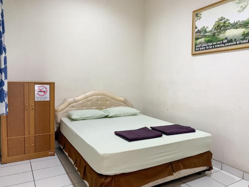 a bedroom with a bed with white sheets and purple pillows at Cozy Homestay Syariah Mitra RedDoorz Bandung in Bandung
