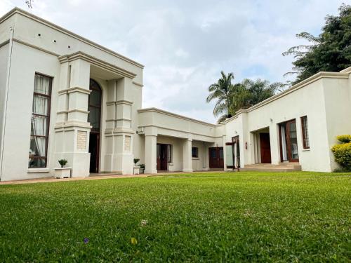 a large white building with a green lawn at Telestai Guest House in White River