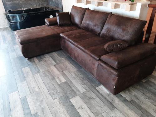 - un canapé en cuir brun dans le salon dans l'établissement la chaumière des barthes, à Laussonne