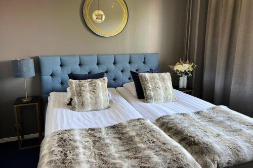 a bedroom with a bed with a blue headboard and pillows at Hotel Golden Circle Suites in Rovaniemi
