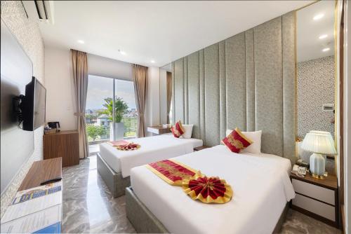 a hotel room with two beds and a television at Tiffany Hotel & Restaurant in Phan Thiet