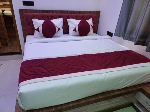 a bedroom with a large bed with red and white pillows at Hotel Shobhani in Deoghar