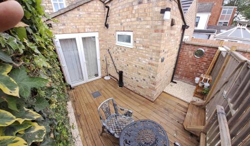 a wooden deck with two chairs and a building at Charming Lincoln Cottage Family & Pet-Friendly in Lincoln