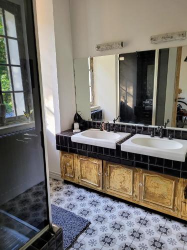 une salle de bain avec deux lavabos et un grand miroir dans l'établissement LE MANOIR PARADI, à Presles-et-Thierny