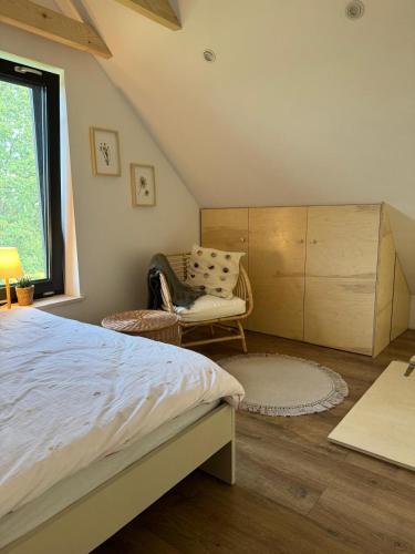 a bedroom with a bed and a chair and a window at Chatka ChoćCo in Ryglice