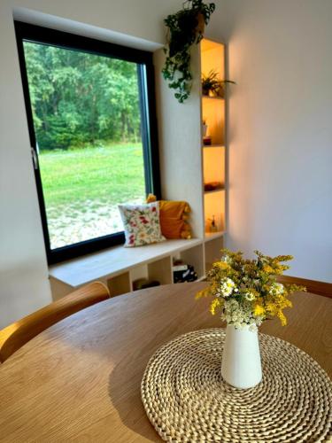 a vase of flowers on a table with a window at Chatka ChoćCo in Ryglice