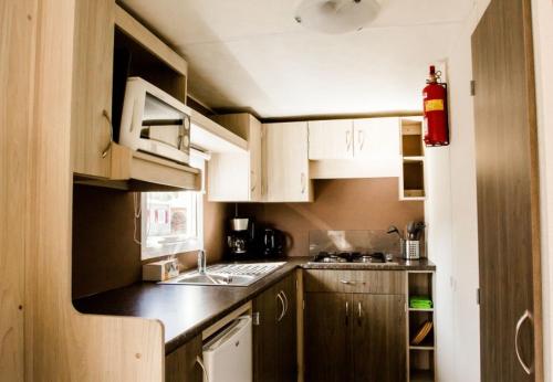 a small kitchen with white cabinets and a sink at Luxe chalet in Harderwijk