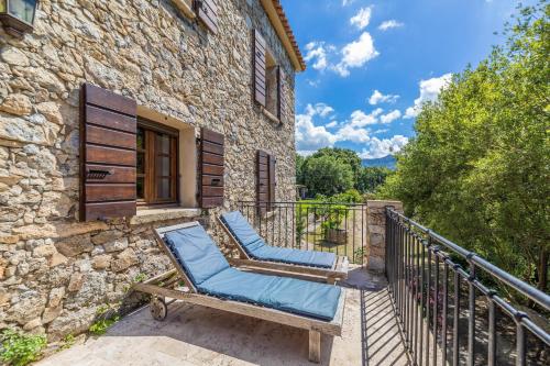 a pair of chairs on a balcony of a stone building at Domaine du Reginu in Santa-Reparata-di-Balagna