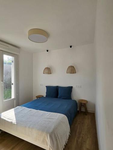 une chambre avec un lit avec des oreillers bleus et une fenêtre dans l'établissement Sejour détente en bord de mer au gîte des falaises, à Plouha