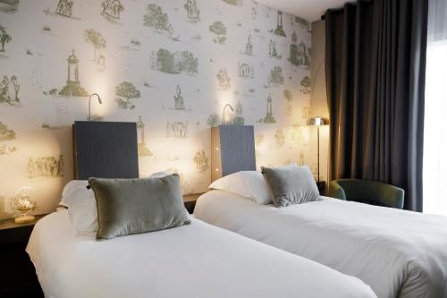 two beds in a hotel room with wallpaper at Best Western Plus Hôtel Gergovie in Pérignat-lès-Sarliève
