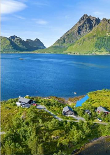 an aerial view of a lake with houses and mountains at Sildpollnes Lodge in Vestpollen