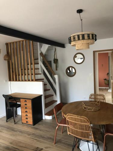 une salle à manger avec une table et des chaises et des escaliers dans l'établissement La loc donvillaise, à Donville-les-Bains