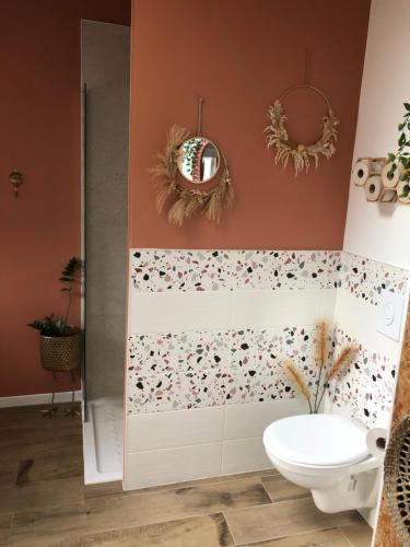 a bathroom with a toilet and flowers on the wall at La loc donvillaise in Donville-les-Bains