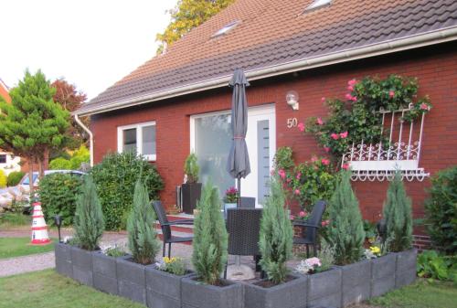 a house with an umbrella and chairs in front of it at FeWo-Möwenpaar-Norden-Norddeich in Norden