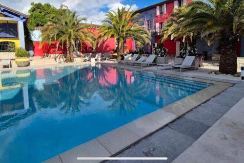 a pool at a hotel with palm trees and buildings at Dépendance de 45m2 à louer in Saint-Vite