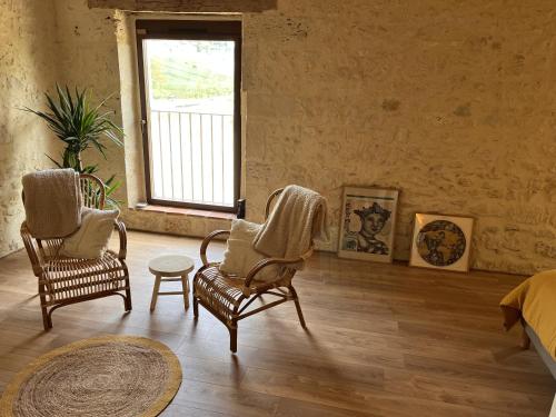 a bedroom with two chairs and a table and a window at Gîte L'Etable - Domaine Lassalle Saint-créac in Saint-Créac