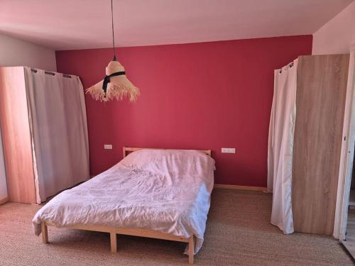 une chambre avec un lit et un mur rouge dans l'établissement maison de village tout confort, à Cruzy