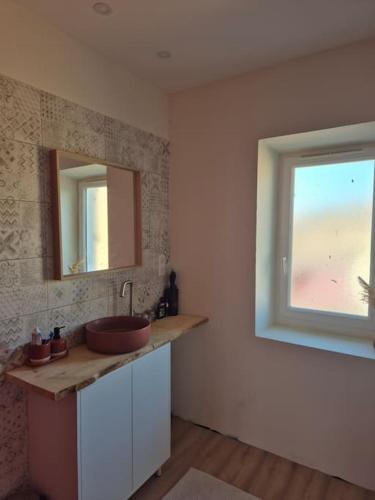 une salle de bain avec un lavabo et une fenêtre dans l'établissement maison de village tout confort, à Cruzy