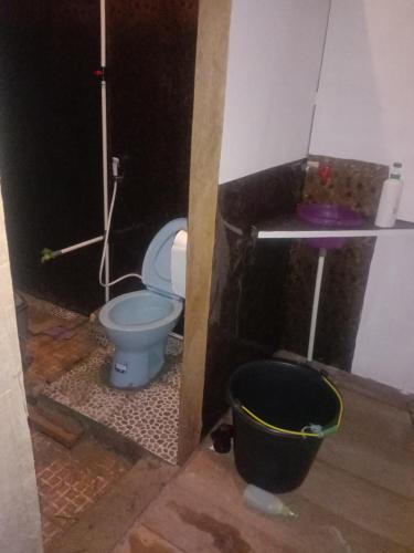 a bathroom with a blue toilet and a bucket at Amfriwen Homestay in Yennanas Besir