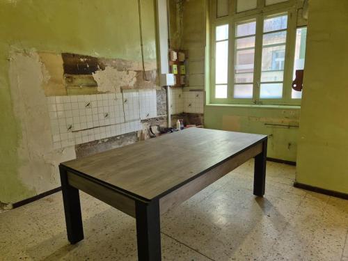 une table en bois dans une pièce vide avec fenêtre dans l'établissement maison de village tout confort, à Cruzy