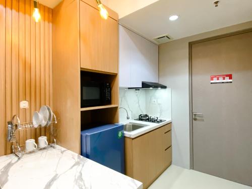 a small kitchen with a sink and a refrigerator at Homey and Minimalist 1BR Vasanta Innopark Apartment By Travelio in Cikarang