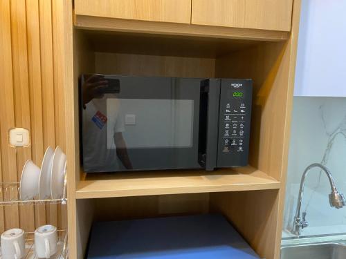 a person taking a picture of a microwave in a kitchen at Homey and Minimalist 1BR Vasanta Innopark Apartment By Travelio in Cikarang