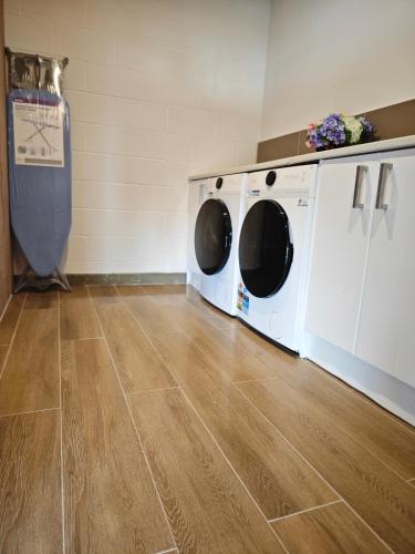 a laundry room with two washing machines and a wooden floor at Sea view 5 bedroom holiday house in Whangaparaoa