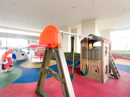 a play room with a slide and swings at Homey and Minimalist 1BR Vasanta Innopark Apartment By Travelio in Cikarang