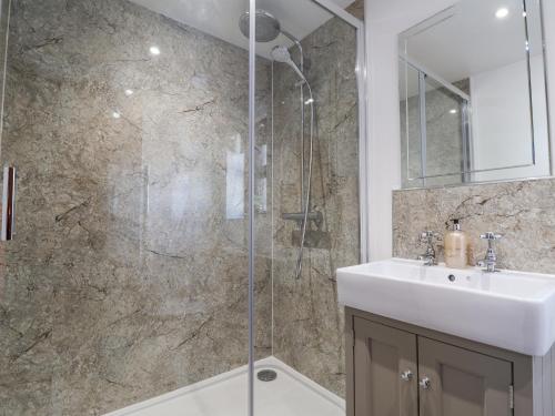 un bagno con lavandino e doccia in vetro di Coach Cottage a Colyton